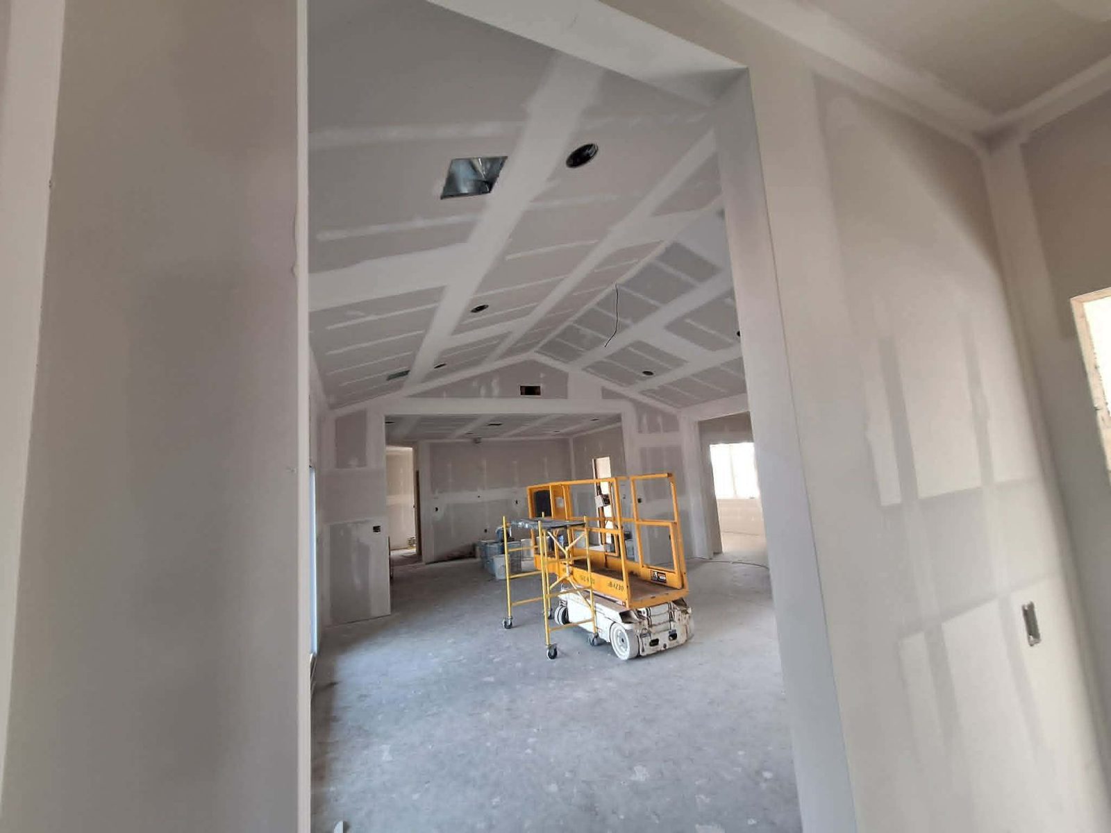 Large open room with finished drywall walls and lift